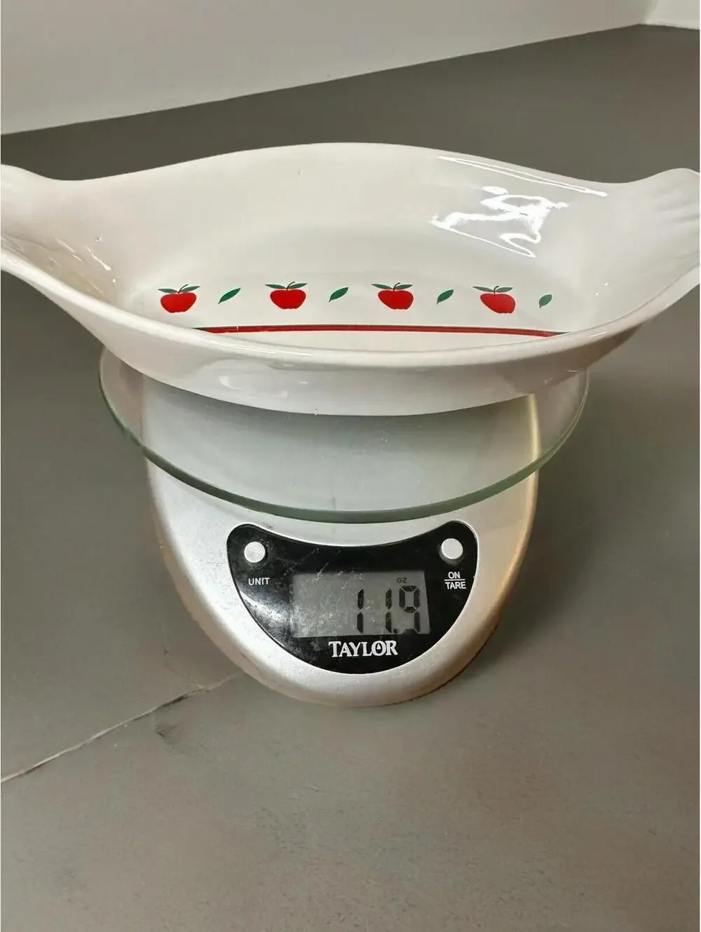 White ceramic oval au gratin dish with red apple and green leaf decoration.